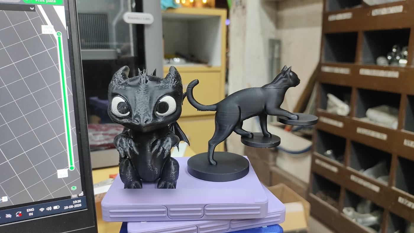 A printed dragon and a printed cat standing on a nameplate on the shop bench.